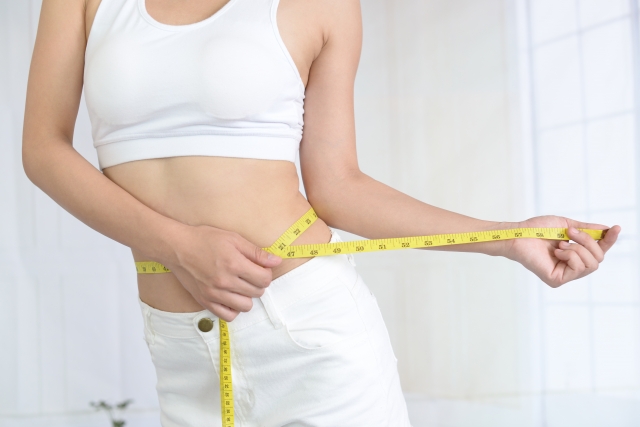 メジャーでお腹を測る女性