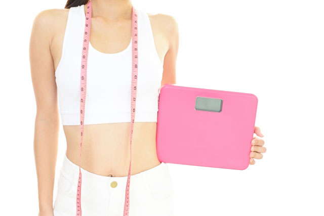 体重計を持つ女性